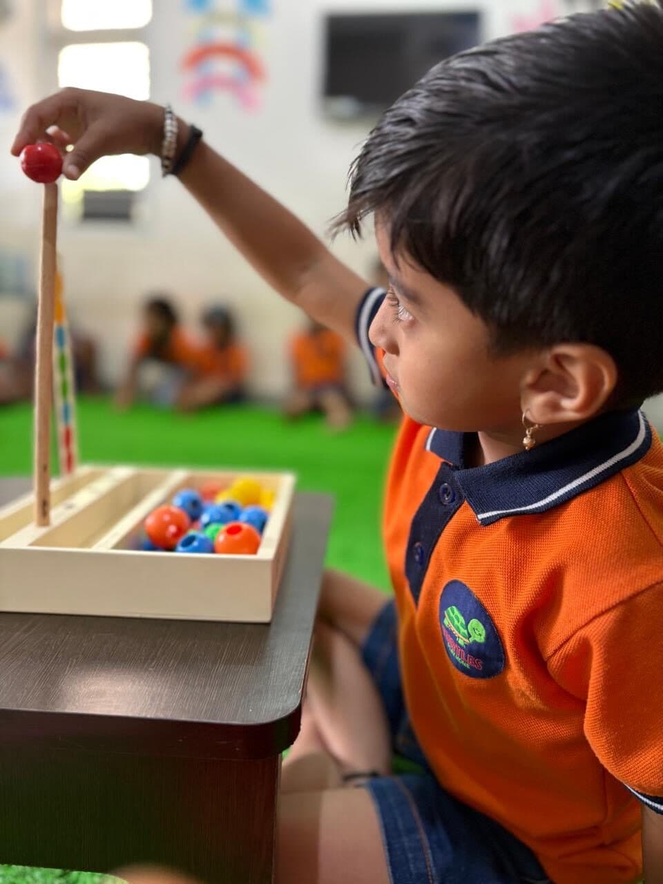 A preschooler threading colourful beads during a Montessori fine-motor activity at Turtles Play Home