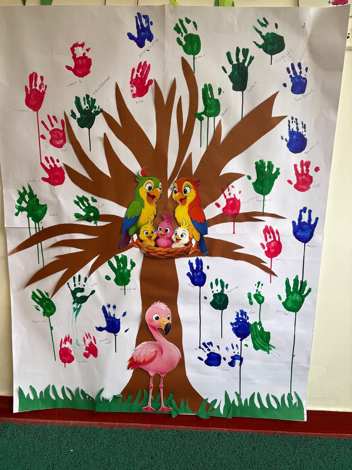 A colourful handprint tree artwork made by Turtles Play Home children, decorated with parrots and a flamingo